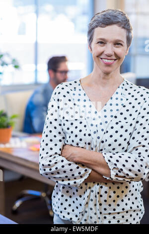 Smiling woman standing arms crossed avec son partenaire derrière Banque D'Images