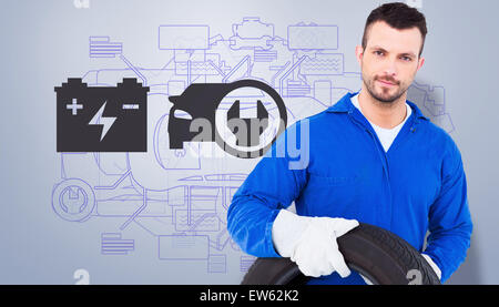 Portrait of male mechanic holding tire Banque D'Images