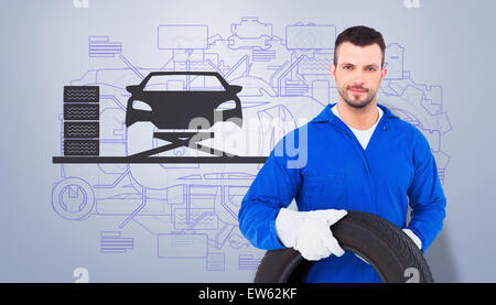 Portrait of male mechanic holding tire Banque D'Images