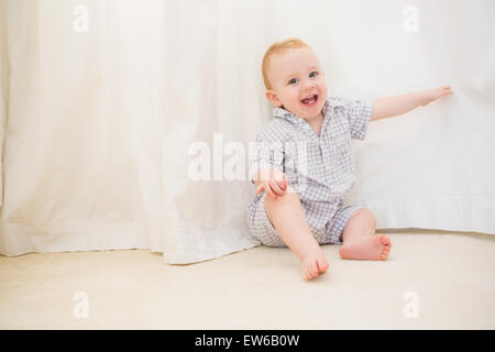 Cute baby boy sitting on floor Banque D'Images