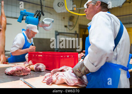 Deux bouchers au travail avec du porc à la boucherie Banque D'Images