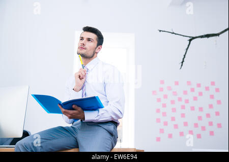 Pensive businessman assis sur la table avec dossier et jusqu'à la Banque D'Images