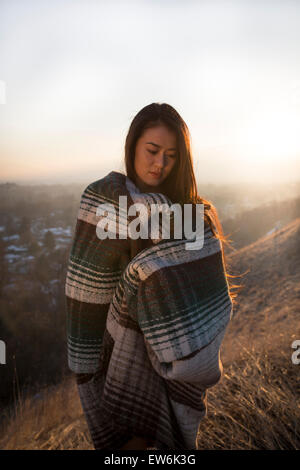 Une fille asiatique pose dans une couverture au coucher du soleil plus petite ville. Banque D'Images