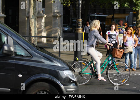 Un cycliste et une voiture roulant a adopté les piétons attendent pour traverser la rue aux passages pour piétons à Trafalgar Square, Londres. Banque D'Images