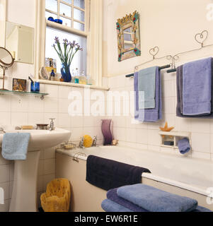 Serviettes bleu sur une grille au-dessus de baignoire en petite salle de bains au carrelage blanc années 90 Banque D'Images