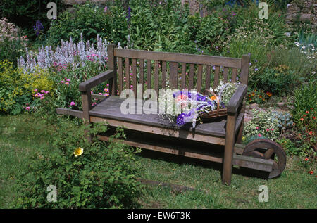 Banc en bois à roues avec un trug de fleurs d'été dans un pays jardin Banque D'Images