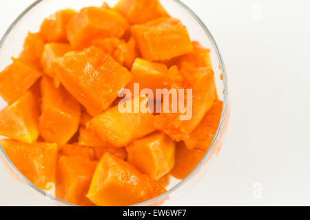 Morceaux de papaye, Carica papaya, dans un bol en verre sur un fond blanc avec copyspace Banque D'Images