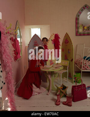 Portrait de deux petites filles s'habillant vers le haut dans une chambre de style économique des années 90 pour un usage éditorial uniquement Banque D'Images