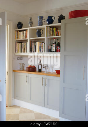 Pichets de poterie et des livres de cuisine sur des étagères dans une cuisine moderne avec armoires gris pâle Banque D'Images