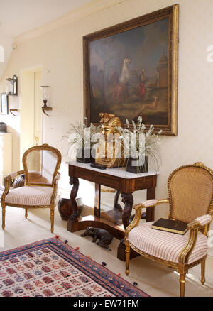 Chaises de style français doré de chaque côté sur du marbre surmontée Table console avec de fausses plantes en salle traditionnelle Banque D'Images