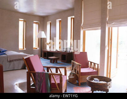 Coussins de fauteuils en bois de rose en français moderne chambre avec des stores en lin blanc sur les portes en verre pour terrasse Banque D'Images