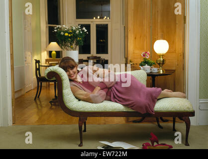 Jeune femme couchée sur une chaise longue dans un salon 70 Banque D'Images