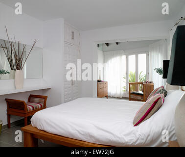 Couette blanche sur lit dans chambre avec côtières blanc simple voile blanc sur les rideaux des fenêtres à la française Banque D'Images