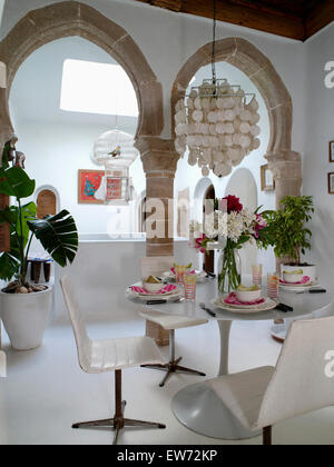 Abat-jour au-dessus de la coquille et des chaises en cuir blanc Tulip set de table pour le déjeuner dans la salle à manger marocaine avec des arches en pierre Banque D'Images