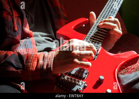 Une vue rapprochée d'un homme jouant de sa guitare rouge Banque D'Images