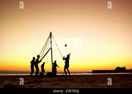 Silhouettes d'un groupe de jeunes qui jouent au beach-volley sur la plage en Bretagne, France Banque D'Images
