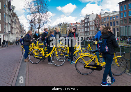 Groupe de touristes sur des vélos jaunes dans le centre d'amsterdam Banque D'Images