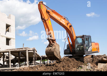 Digger orange permet de creuser le sol en préparation de nouveaux appartements pour les jeunes familles en ville Ufa Bashkortostan la Russie en juin 2015 Banque D'Images