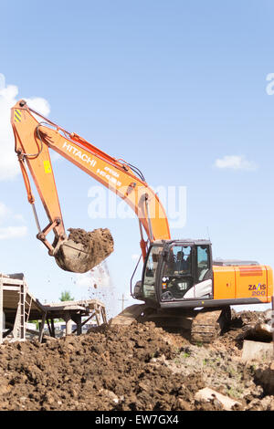 Digger orange permet de creuser le sol en préparation de nouveaux appartements pour les jeunes familles en ville Ufa Bashkortostan la Russie en juin 2015 Banque D'Images