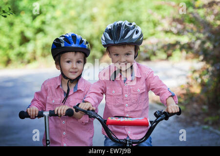 Portrait de deux garçons dans le parc, équitation, vélo et scooter, smiling at the camera Banque D'Images