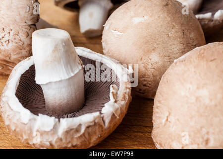 Gros plan sur trois champignon champignons sur planche à découper en bois deux face à l'aide de capuchons et de l'une à l'envers Banque D'Images