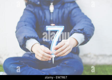 Girl sitting cross legged tenant une bougie numéro 7 Banque D'Images