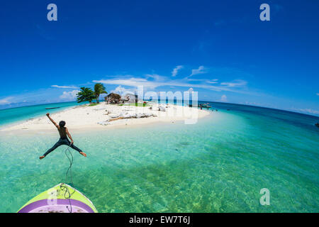 Teenage boy Jumping off l'avant d'un bateau dans la mer, Semporna, Sabah, Malaisie Banque D'Images