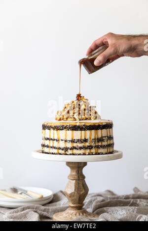 La main de l'homme couler sur une éponge chocolat Caramel et gâteau crème au beurre Banque D'Images