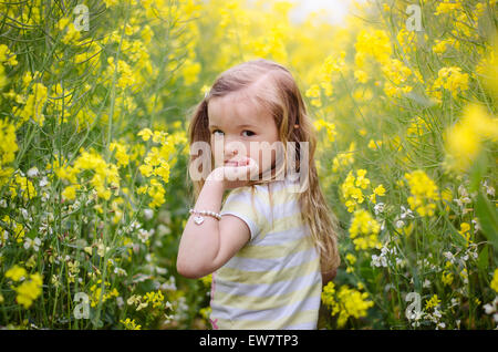 À la fille par-dessus son épaule dans un pré de fleurs jaunes Banque D'Images