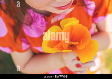 Gros plan d'une fille tenant des coquelicots orange Banque D'Images