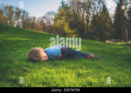 Joyeux garçon allongé sur l'herbe reposant Banque D'Images