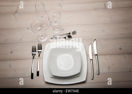 Set de table avec assiettes, couverts et verres sur table en bois Banque D'Images