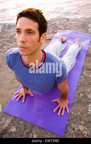 Un homme pratiquant le yoga sur un éperon rocheux au-dessus de l'océan Pacifique au nord, l'un de Curl Curl Sydneys Plages du Nord. Sy Banque D'Images