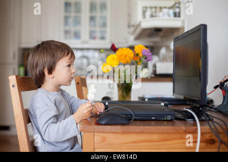 Adorable petit garçon, avoir une sucette tout en regardant cartoon sur ordinateur Banque D'Images