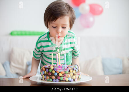 Belle adorable petit garçon de quatre ans en chemise verte, qui fête son anniversaire, smearing cake maison faits maison, piscine. B Banque D'Images