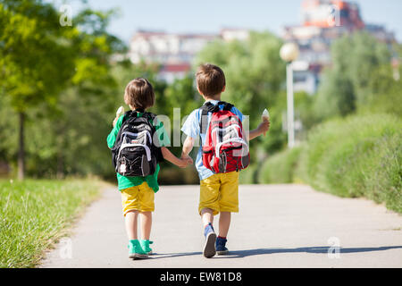 Deux adorables garçons dans des vêtements colorés et sacs à dos, à pied, de la détention et la consommation de crème glacée sous le soleil d'après-midi d'été, la guerre Banque D'Images