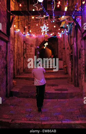 Israël, Jérusalem. 19 Juin, 2015. Jeune garçon marche avec tuyau Shisha dans une ruelle dans le quartier musulman avec lumières de fête pendant le premier vendredi du mois du Ramadan, dans la vieille ville de Jérusalem le 19 juin 2015. Le Ramadan est décrit comme un mois saint de sacrifice et d'adoration pour le peuple musulman, et c'est le mois le plus sacré dans le calendrier islamique. Credit : Eddie Gerald/Alamy Live News Banque D'Images