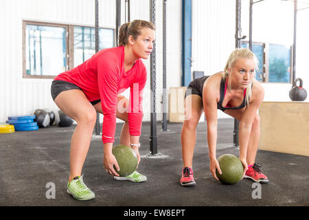 Deux femmes ascenseurs slam balls à la salle de sport Banque D'Images