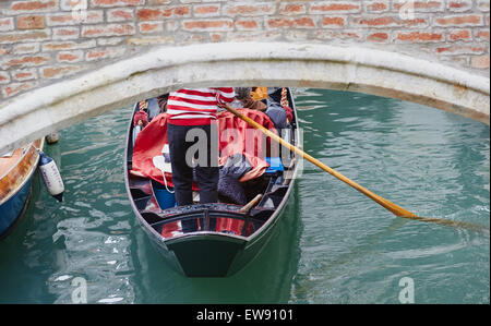 Gondolier en rouge et blanc traditionnel haut rayé l'aviron une gondole sous un pont Castello Venise Vénétie Italie Europe Banque D'Images