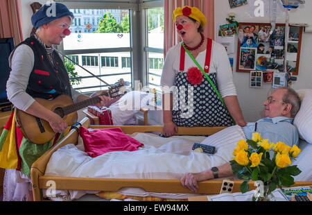 Schwerin, Allemagne. Le 05 juin, 2015. 'Bien' de clowns à l'hôpital (Ines Vowinkel, L) et 'Kiki' (Kerstin Daum) chanter une chanson pour Guenther Piehl lors d'une tournée à travers les pupilles de l'infirmière 'Augustenstift' soins infirmiers à Schwerin, Allemagne, 05 juin 2015. Les clowns ont été visiter les malades atteints de démence et les personnes ayant besoin de soins une fois par mois depuis deux ans. Photo : Jens Buettner/dpa/Alamy Live News Banque D'Images