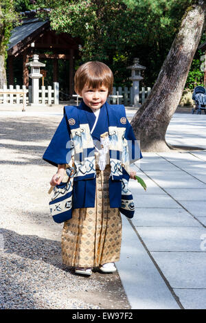 Au Japon, 5 ans caucasien enfant, garçon, habillé en kimono, heureux et excité, souriant debout holding leaf et ventilateur. Vue avant Banque D'Images