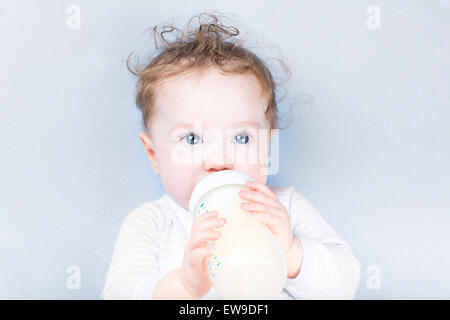 Sweet baby dans un pull bleu boire du lait Banque D'Images