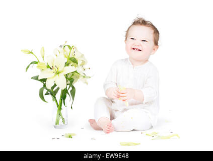 Drôle de petit bébé jouant avec lily fleurs, on white Banque D'Images