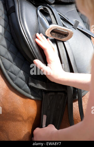 Une femme contrôle de la circonférence sur une selle de cheval Banque D'Images