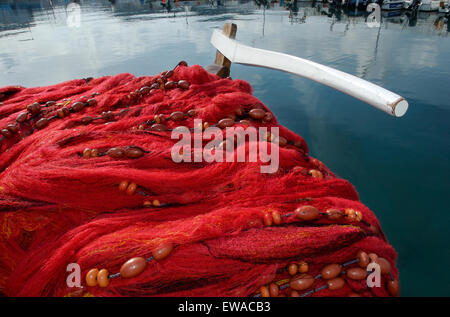 Filets de pêche rouge séchant au soleil en attente de réparation à l'arrière du bateau de pêche post visible. Myrina quay, Limnos ou île de Lemnos, Grèce Banque D'Images