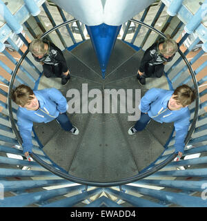 Split, verticalement et horizontalement en miroir image inversée de deux jeunes femmes sur spiral staircase Banque D'Images