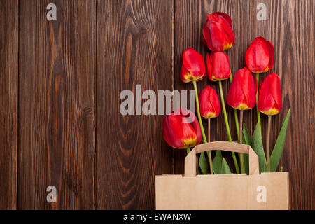 Bouquet de tulipes rouges dans un sac de papier de fond de table en bois avec copie espace Banque D'Images