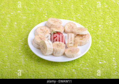 Régime de bananes et fraises plusieurs on white plate Banque D'Images