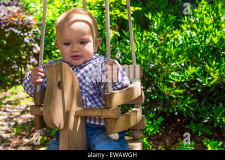 Mignon bébé dans un arbre en bois swing Banque D'Images