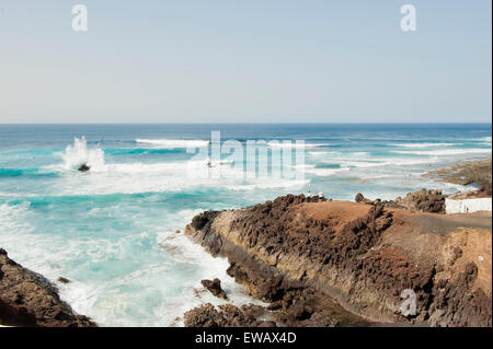 Lanzarote, îles Canaries. Une femme et un homme debout sur un rocher, face à la mer. Broyage des vagues sur les rochers dans la mer. Banque D'Images